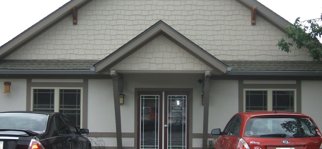 A red car parked in front of a white building.