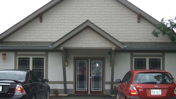 A red car parked in front of a white building.
