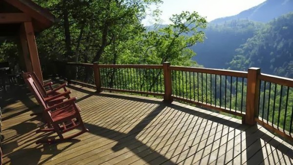 A deck with chairs and trees in the background