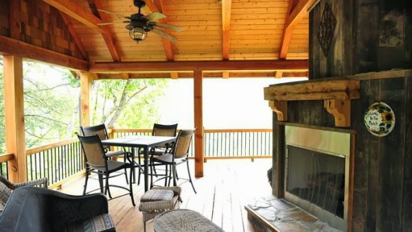 A large open porch with a fireplace and table.