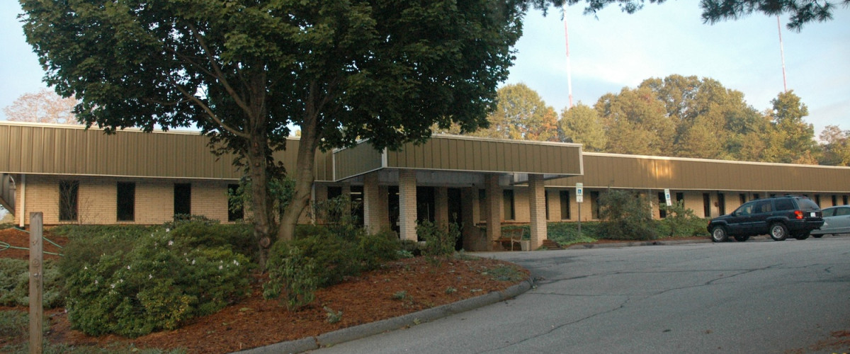 A building with trees and bushes in front of it.